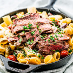 side view shot of a skillet of ribeye steak pasta puttanesca