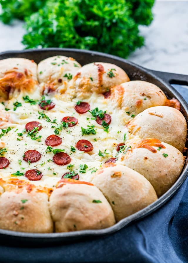 a skillet lined with rolls filled with cheesy pizza dip