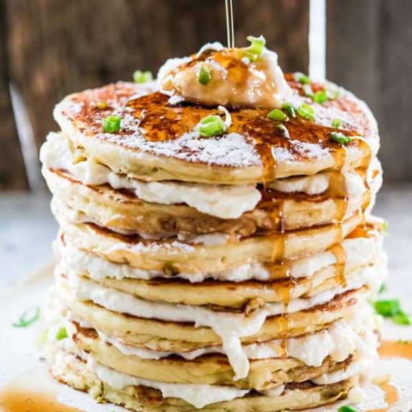 side view shot of syrup being poured over a stack of jalapeno popper pancakes