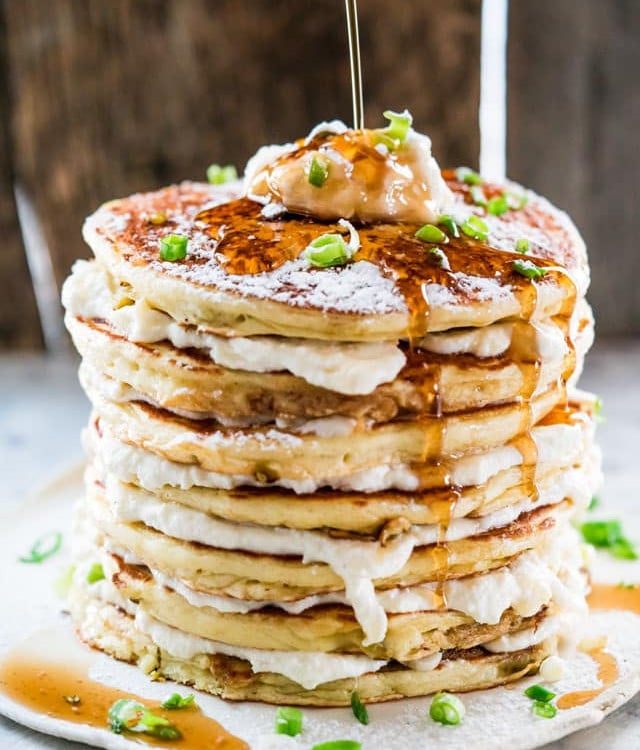 side view shot of syrup being poured over a stack of jalapeno popper pancakes