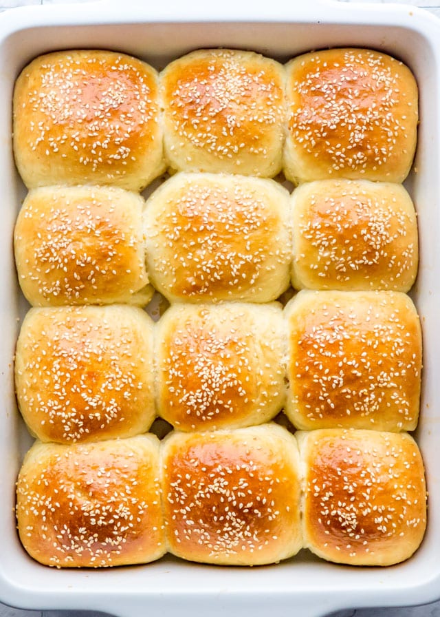 freshly baked buttermilk dinner rolls with sesame seeds in a baking dish