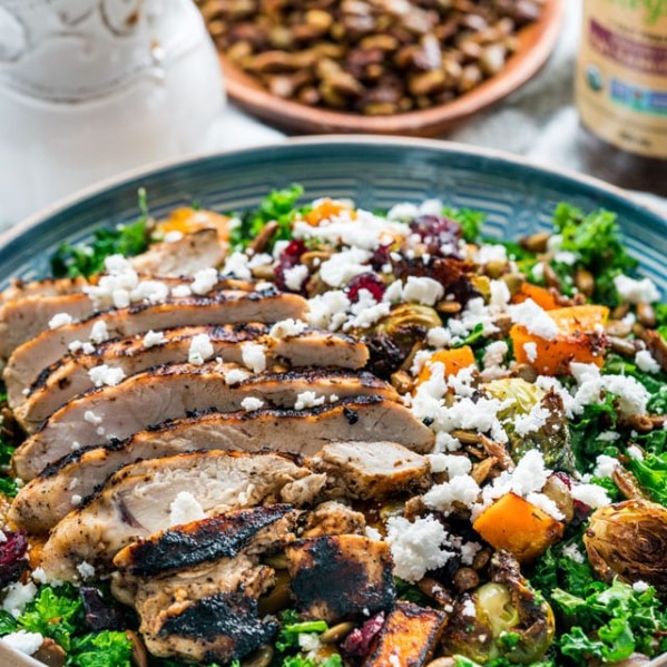 side view shot of the warm kale salad with roasted butternut squash, topped with sliced chicken breast and feta cheese