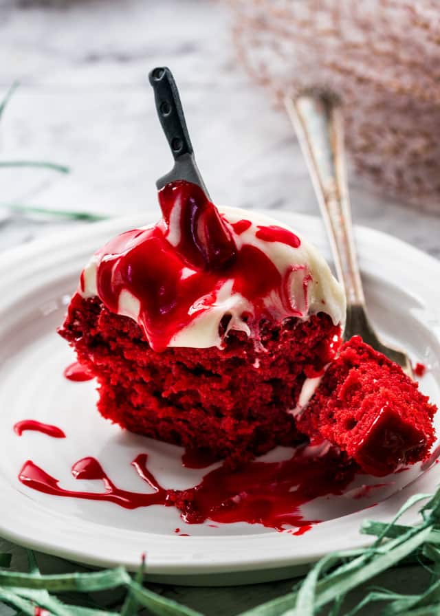 a fork taking a bite out of a red velvet cupcake with a candy knife