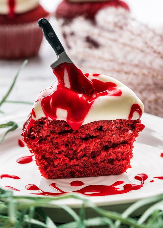 red velvet cupcake cut in half with a candy knife and drizzled with red icing