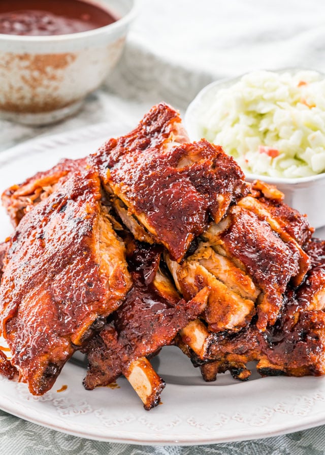 A stack of bbq pork ribs with a bowl of coleslaw