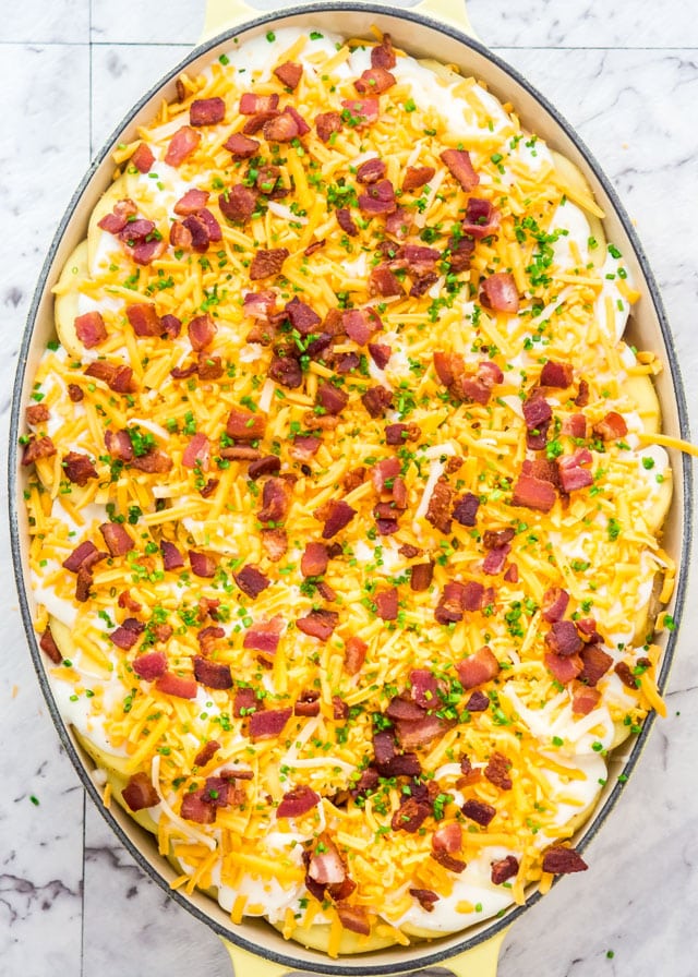 a baking dish full of cheese, bacon, and scalloped potatoes