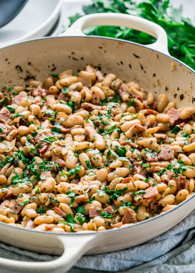 White Beans with Bacon and Herbs in a pan garnished with parsley