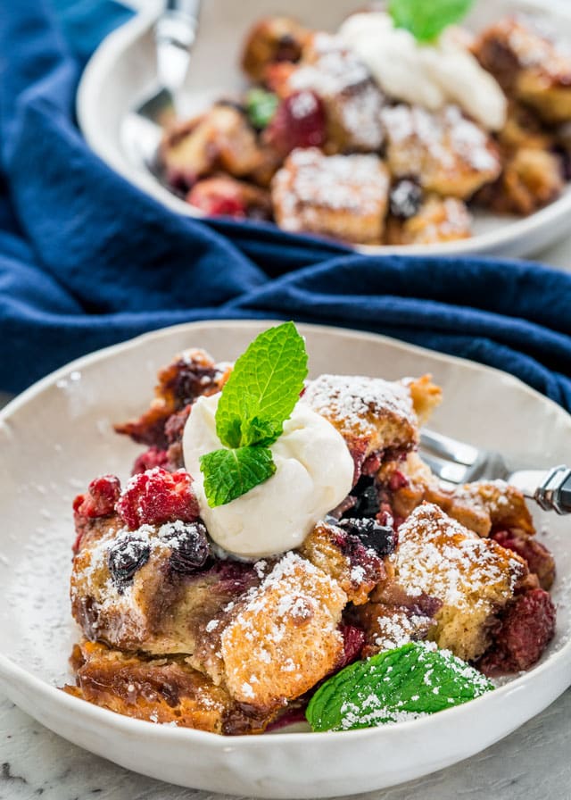 Bowl of Berry Brioche Bread Pudding topped with whipped cream and mint