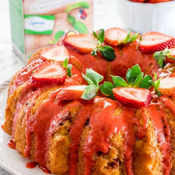 side view shot of a strawberry lemon bundt cake topped with strawberry glaze and sliced fresh strawberries