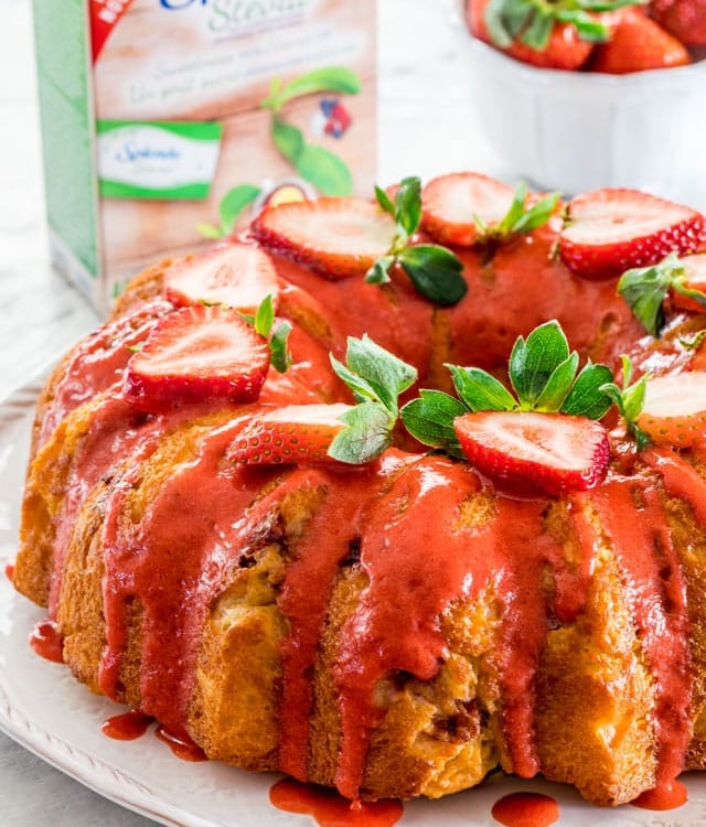 side view shot of a strawberry lemon bundt cake topped with strawberry glaze and sliced fresh strawberries