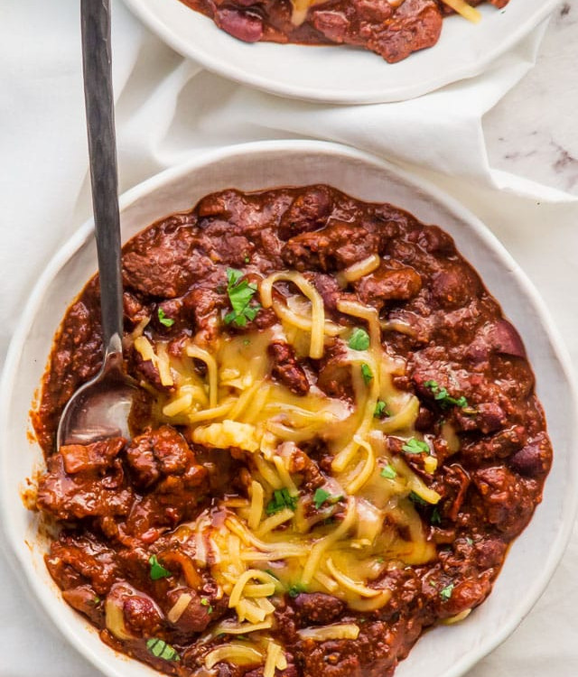 overhead shot of a bowl of chili topped with shredded cheddar cheese