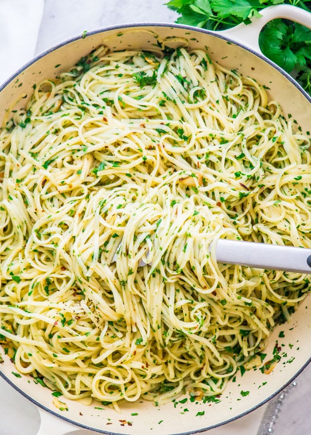 aglio e olio in a skillet with tongs holding pasta