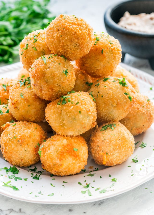 potato croquettes on a white plate with dip in the background