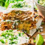 side view shot of chicken enchilada quesadillas stacked and garnished with green onion and a lime wedge