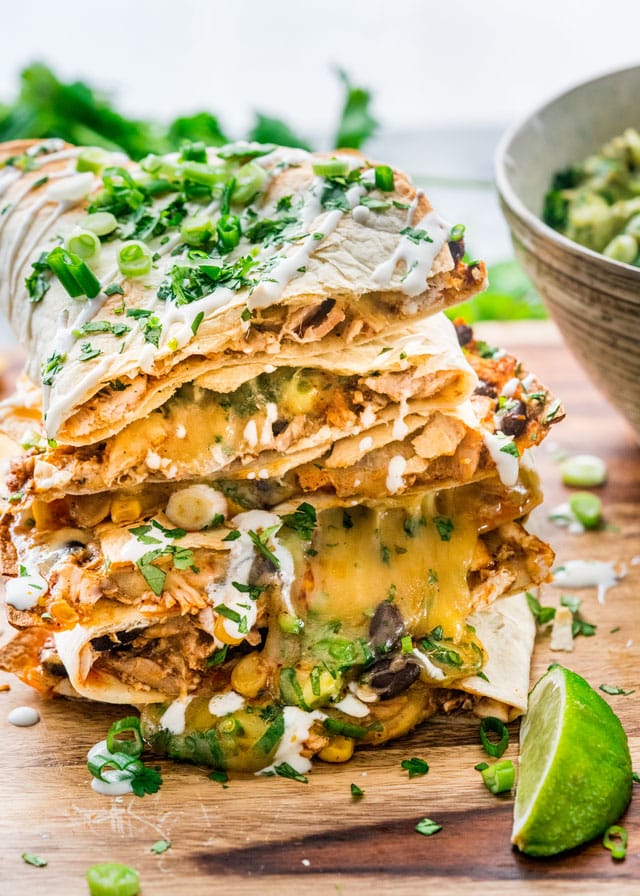 a stack of chicken enchilada quesadillas on a cutting board with a garnish of lime wedge