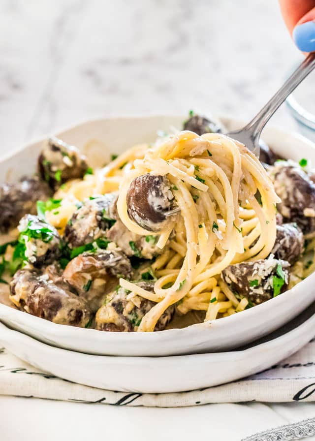 creamy garlic parmesan mushrooms over pasta in two stacked white plates