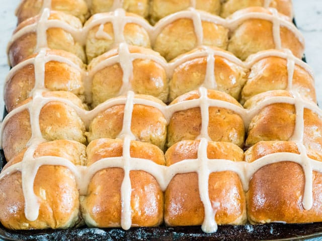 hot cross buns in a baking sheet with cinnamon icing cross
