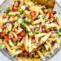 overhead shot of a bowl of italian pasta salad with salad tongs in it