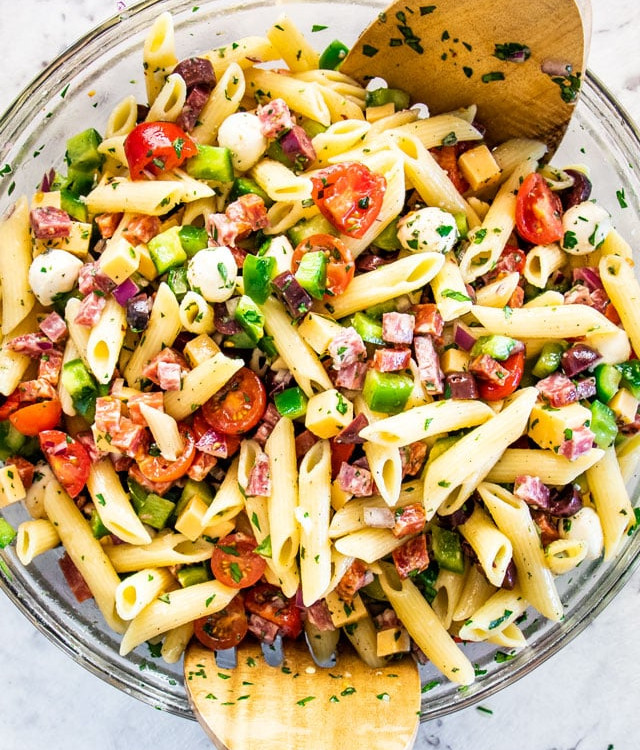 overhead shot of a bowl of italian pasta salad with salad tongs in it