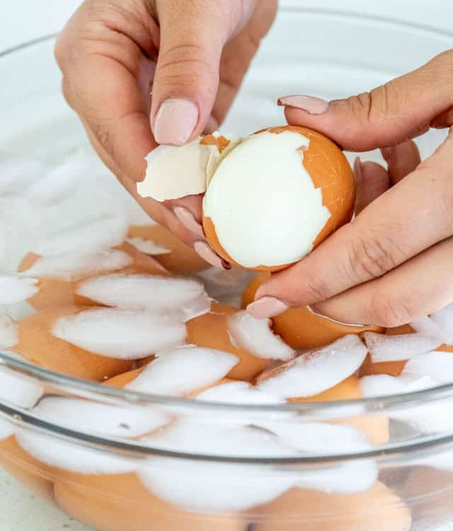 peeling Instant Pot Hard Boiled Eggs in a bowl with ice water