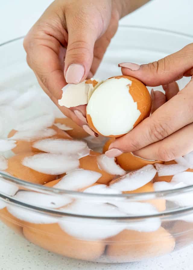 peeling Instant Pot Hard Boiled Eggs in a bowl with ice water