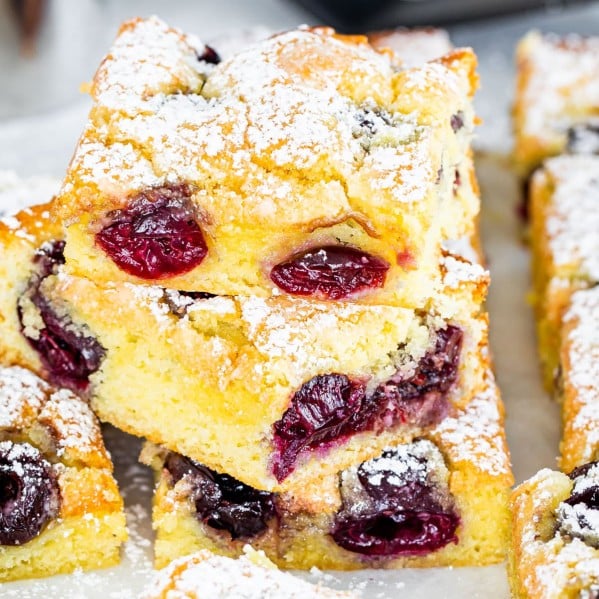 cherry sheet cake slices with a couple stacked on top of each other dusted with powdered sugar