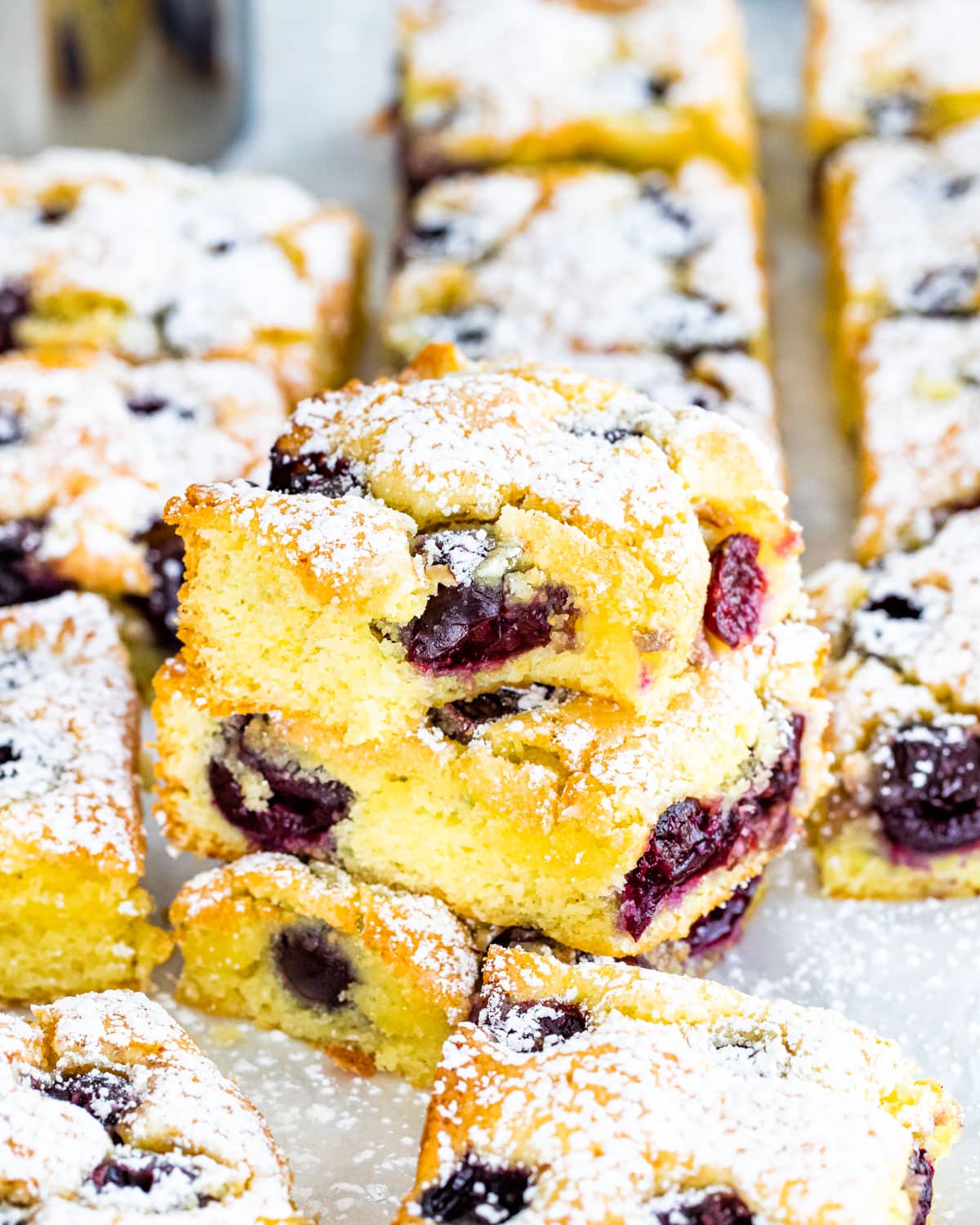 cherry sheet cake slices with a couple stacked on top of each other dusted with powdered sugar
