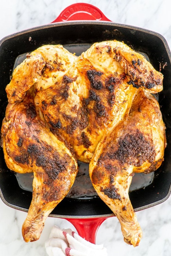 overhead shot of a whole spatchcock chicken in a roasting pan