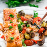 side view shot of a fork taking a bite of salmon and veggies from a plate