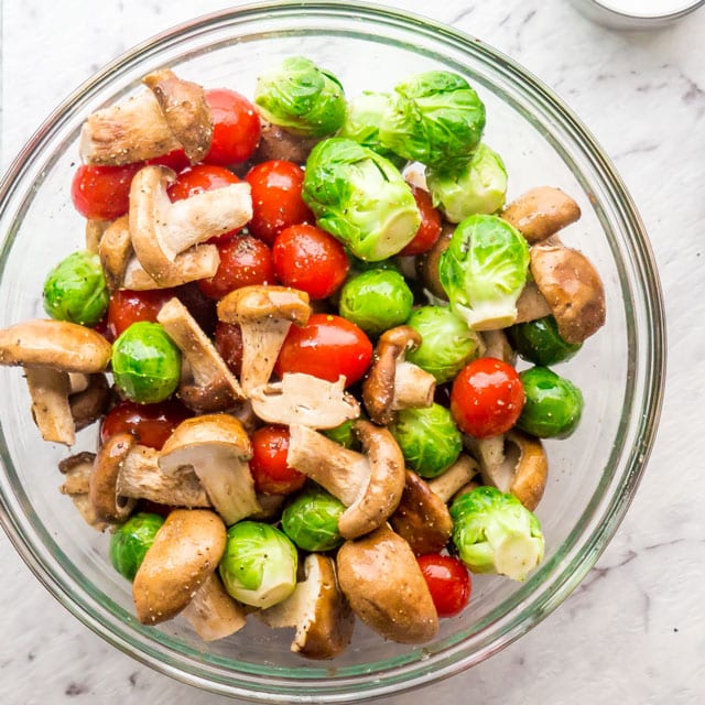 overhead shot of a bowl loaded with brussels sprouts, shiitake mushrooms and cherry tomatoes