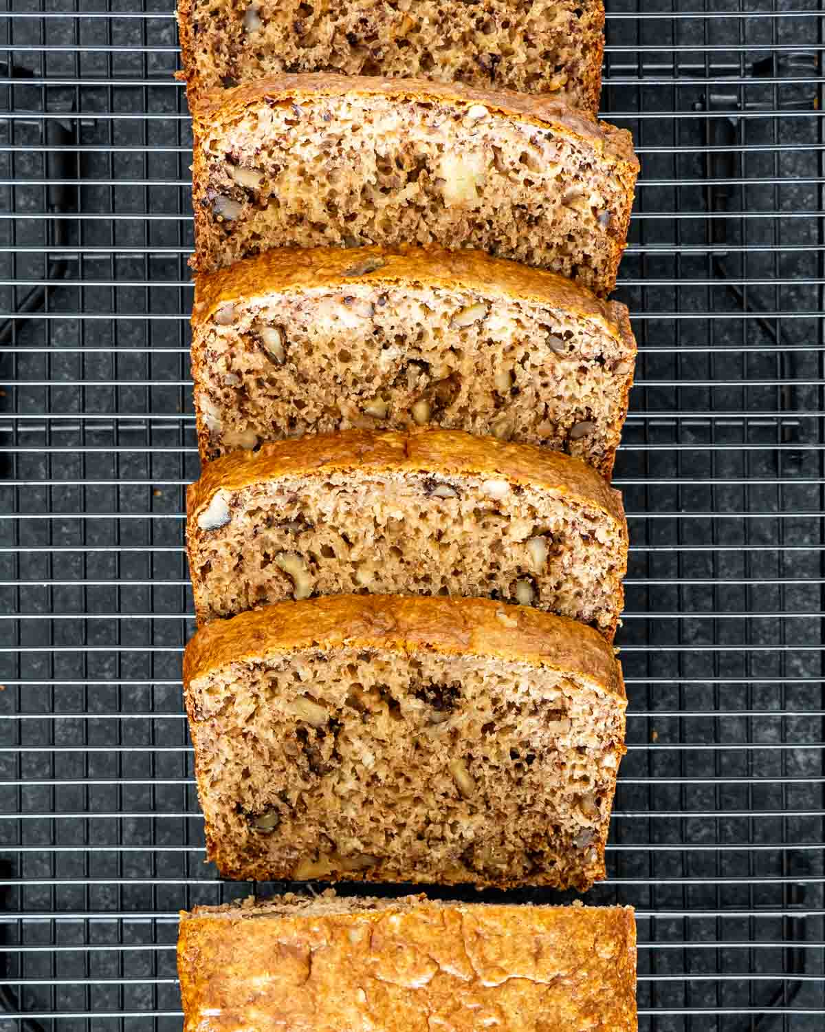 slices of banana nut bread on a black cooling rack.