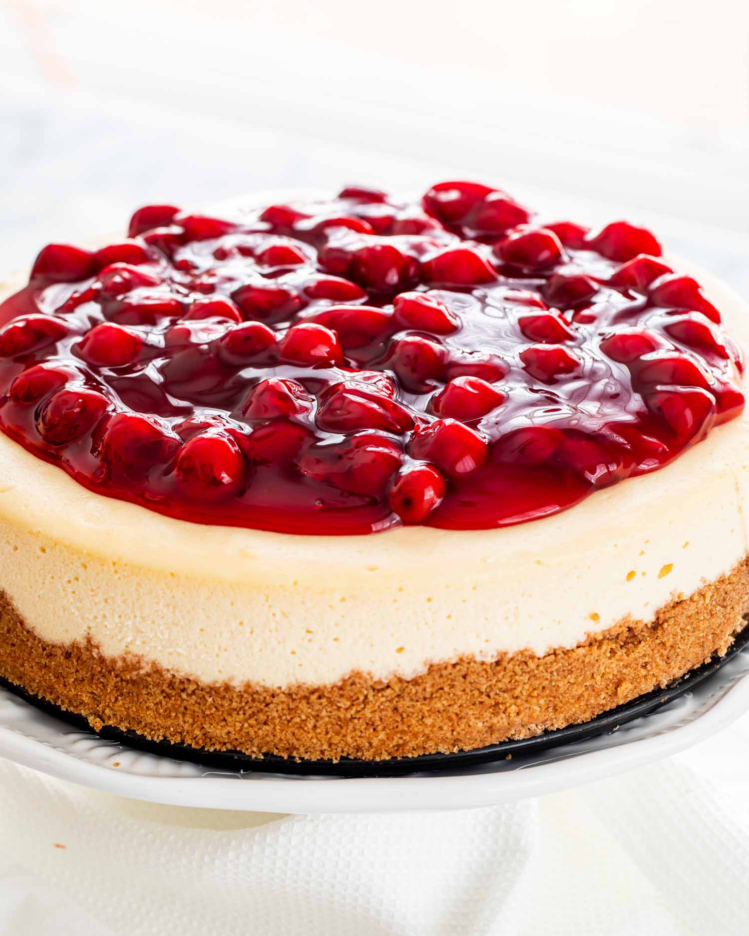 a cheesecake with cherry topping on a cake platter.