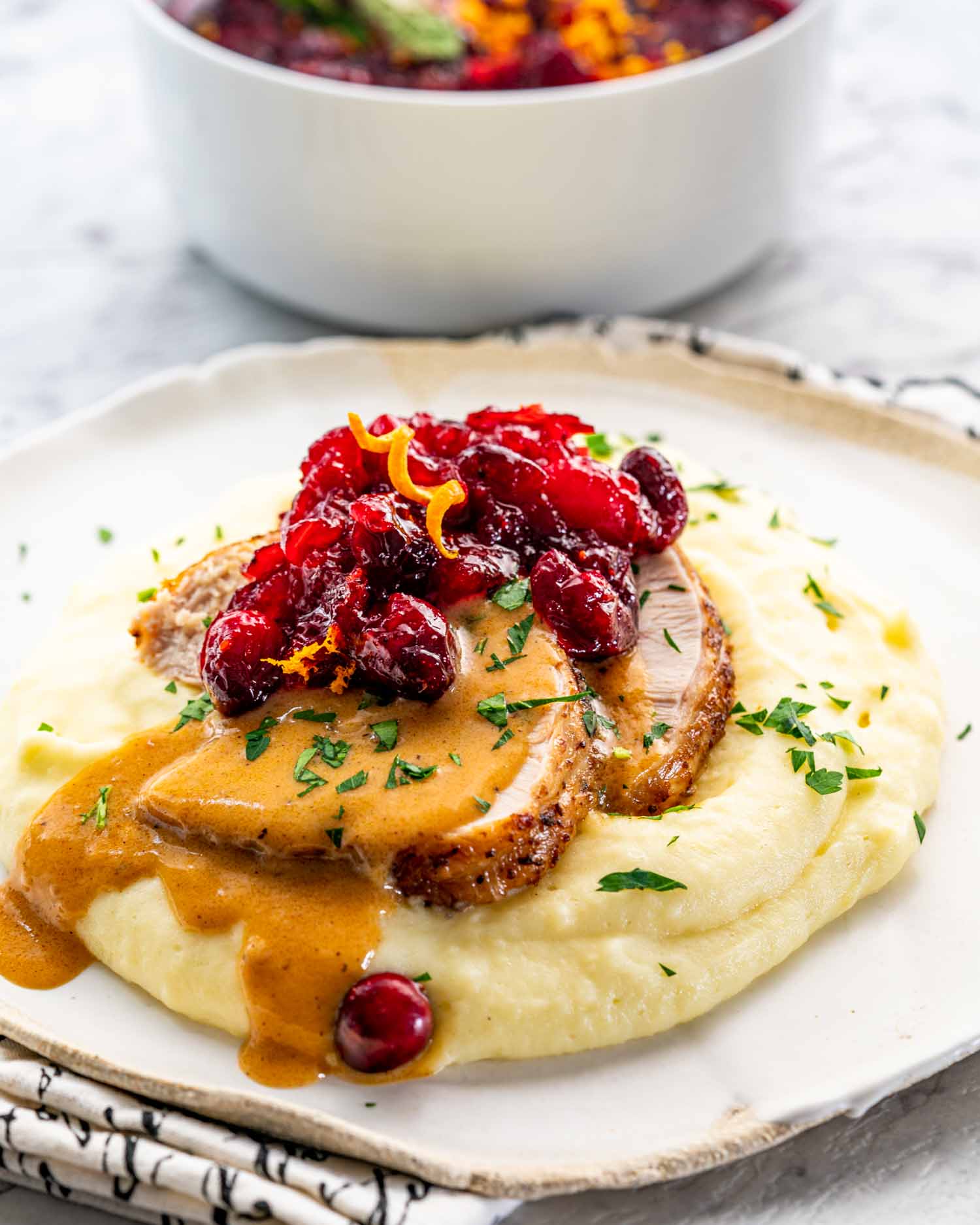 instant pot turkey breast cut in slices over a bed of mashed potatoes garnished with gravy, parsley and cranberries.