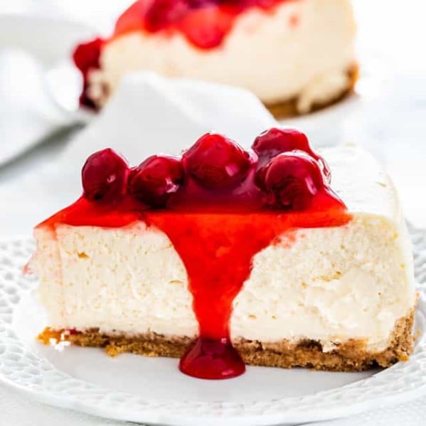 side view shot of a slice of new york style cheesecake with cherry topping on a plate