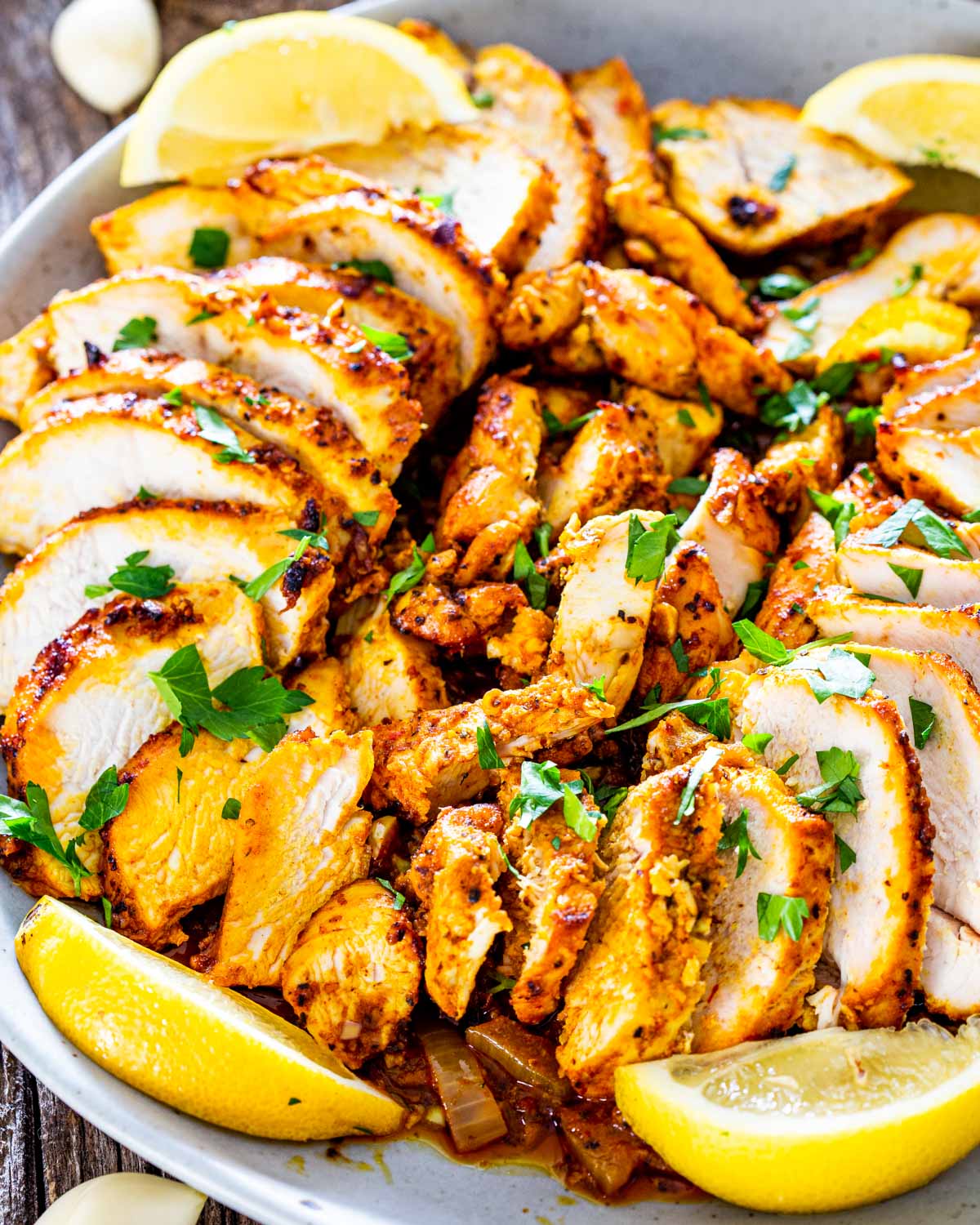 chicken shawarma sliced on a plate garnished with lemon wedges.