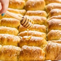 side view shot of a hand drizzling honey over the rolls