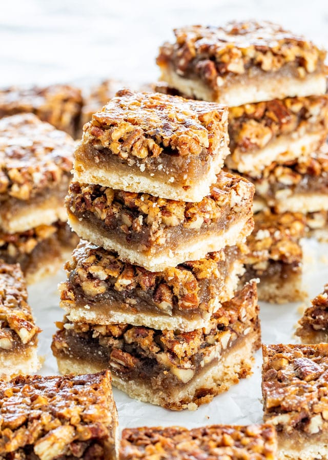 Pecan Pie Bars stacked on top of each other over parchment paper