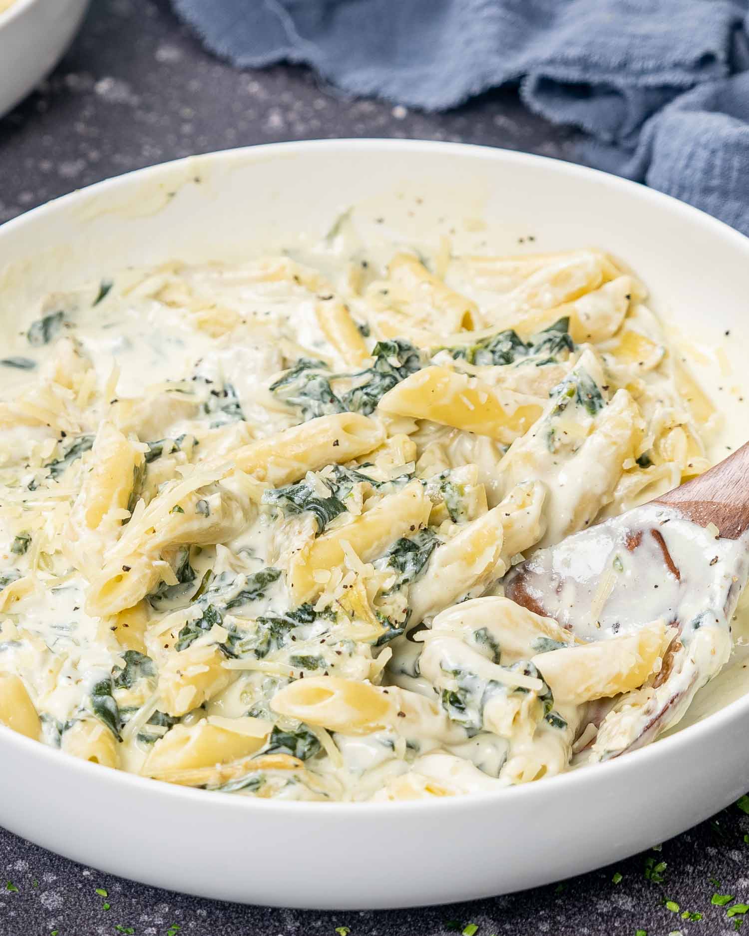 freshly made spinach artichoke pasta in a white bowl.