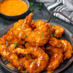 a metal plate filled with bang bang shrimp, crispy and fried and drizzled with a delicious bang bang sauce.