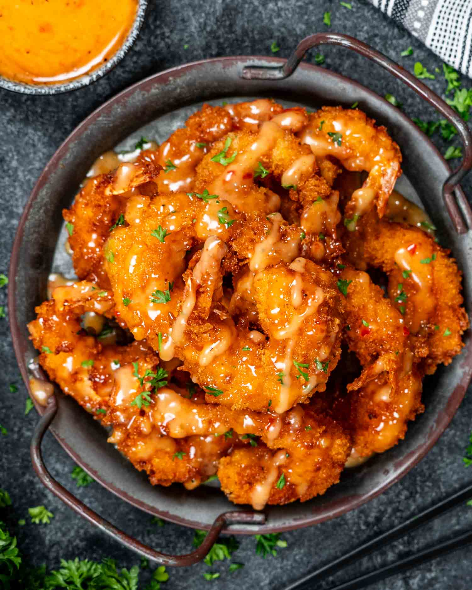 a metal plate filled with bang bang shrimp, crispy and fried and drizzled with a delicious bang bang sauce.