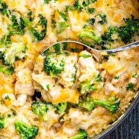 a serving spoon inside a skillet with chicken broccoli rice casserole.