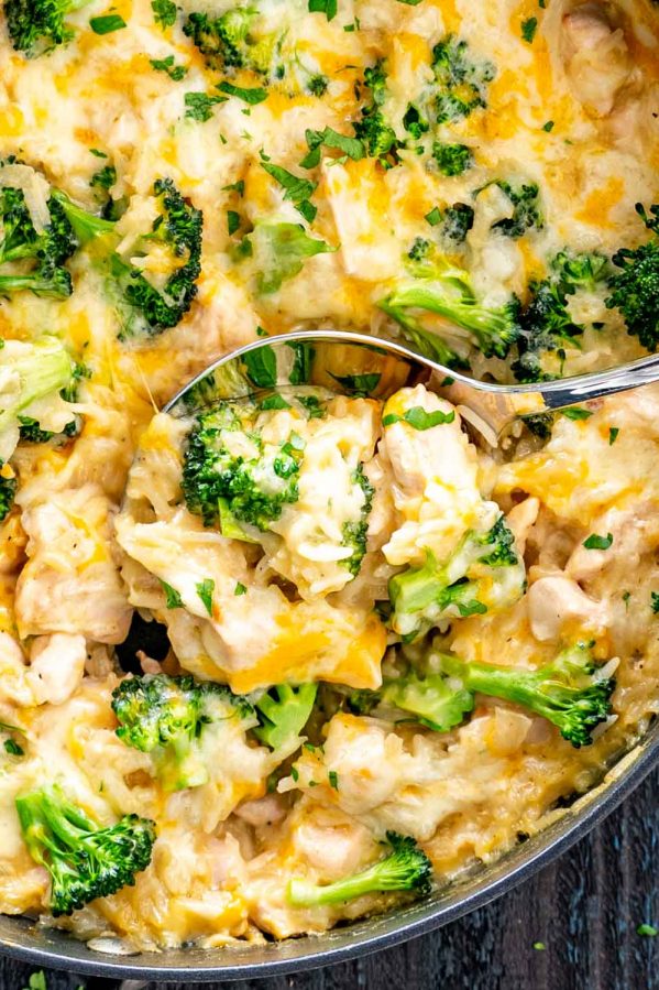 a serving spoon inside a skillet with chicken broccoli rice casserole.