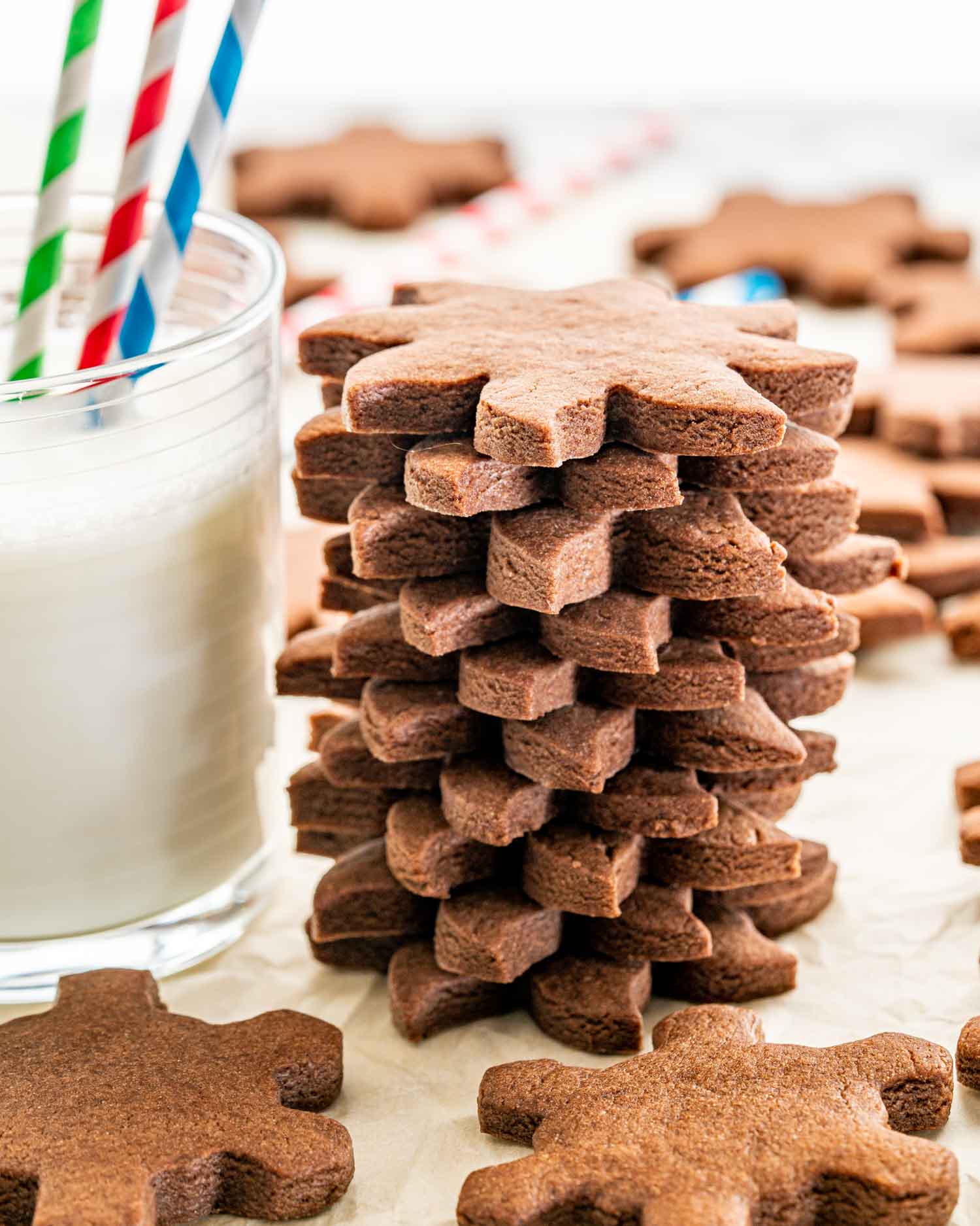 a stack of chocolate sugar cookies next to a glass of milk.