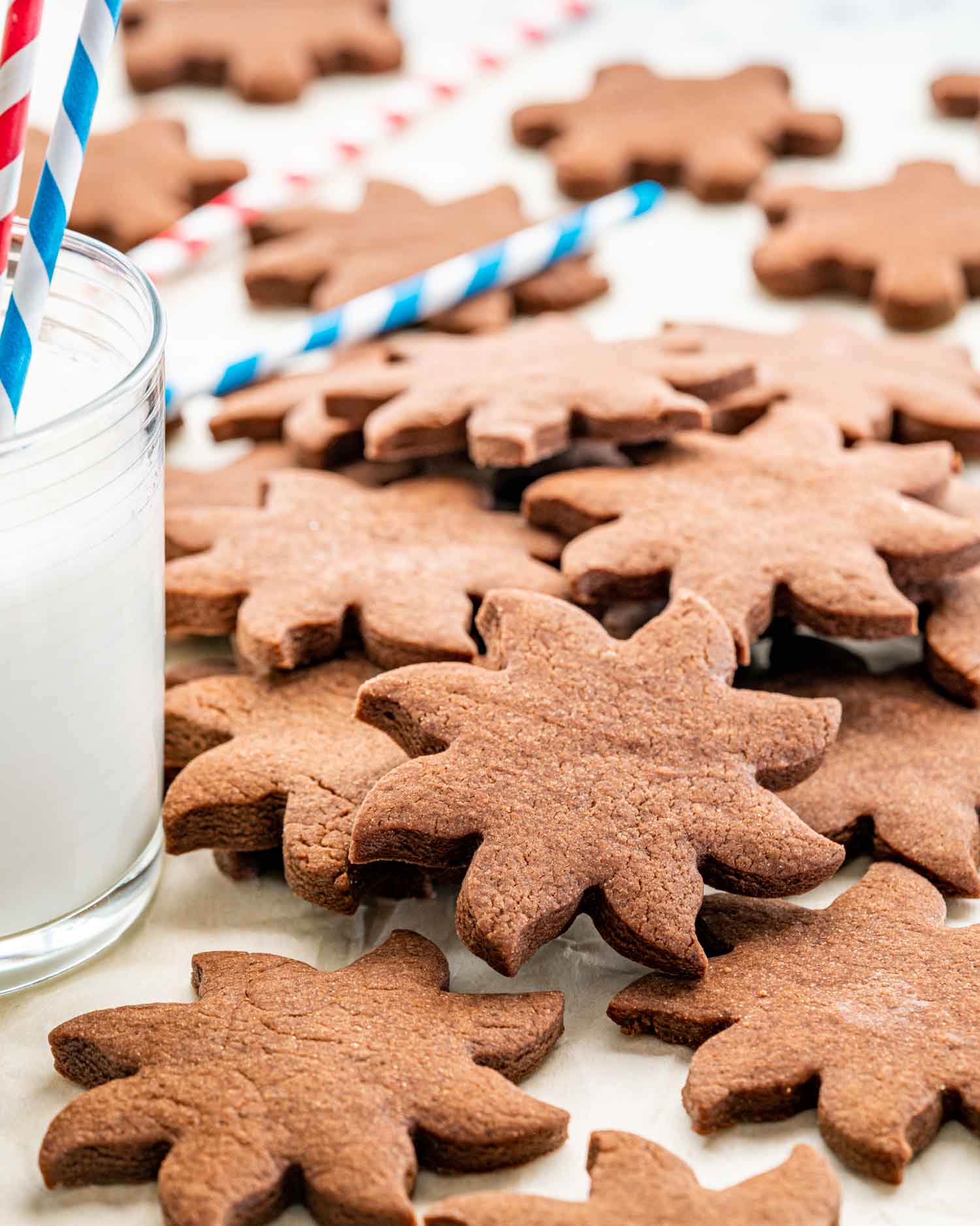 a pile of chocolate sugar cookies next to a glass of milk.