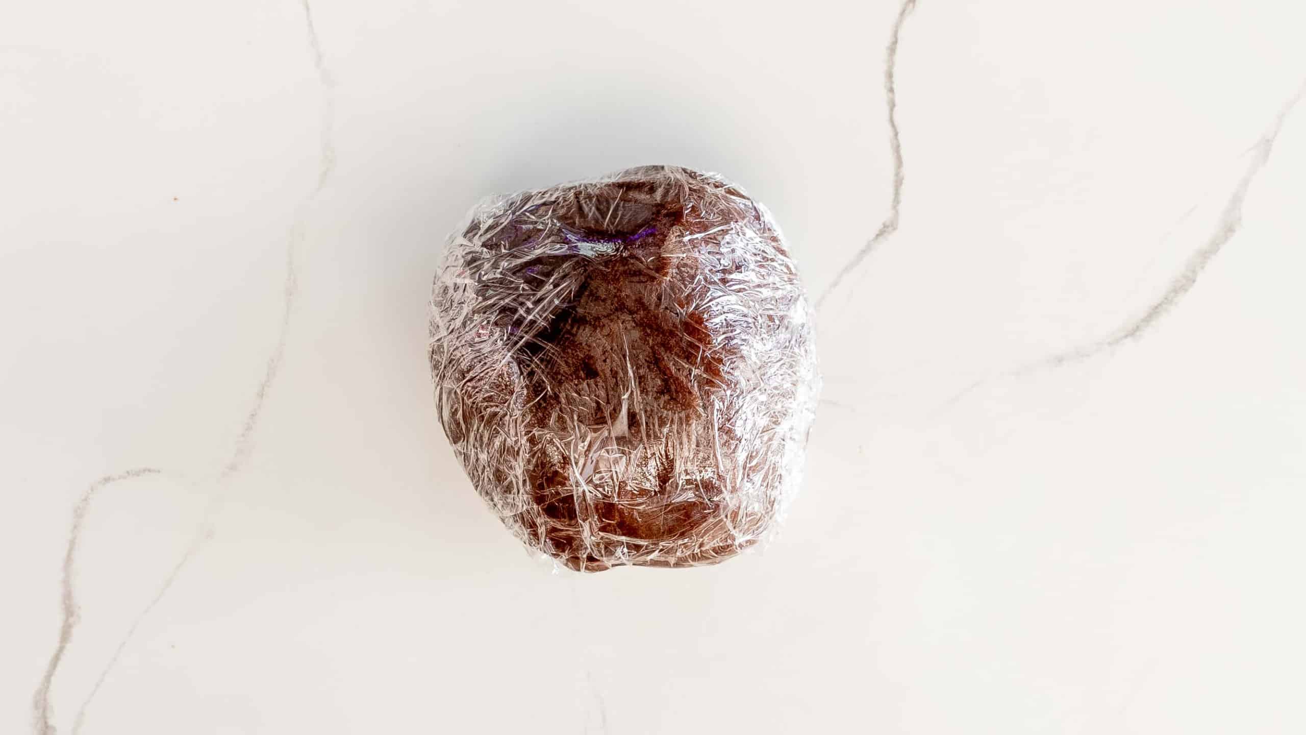 a ball of chocolate sugar cookie dough in plastic wrap.