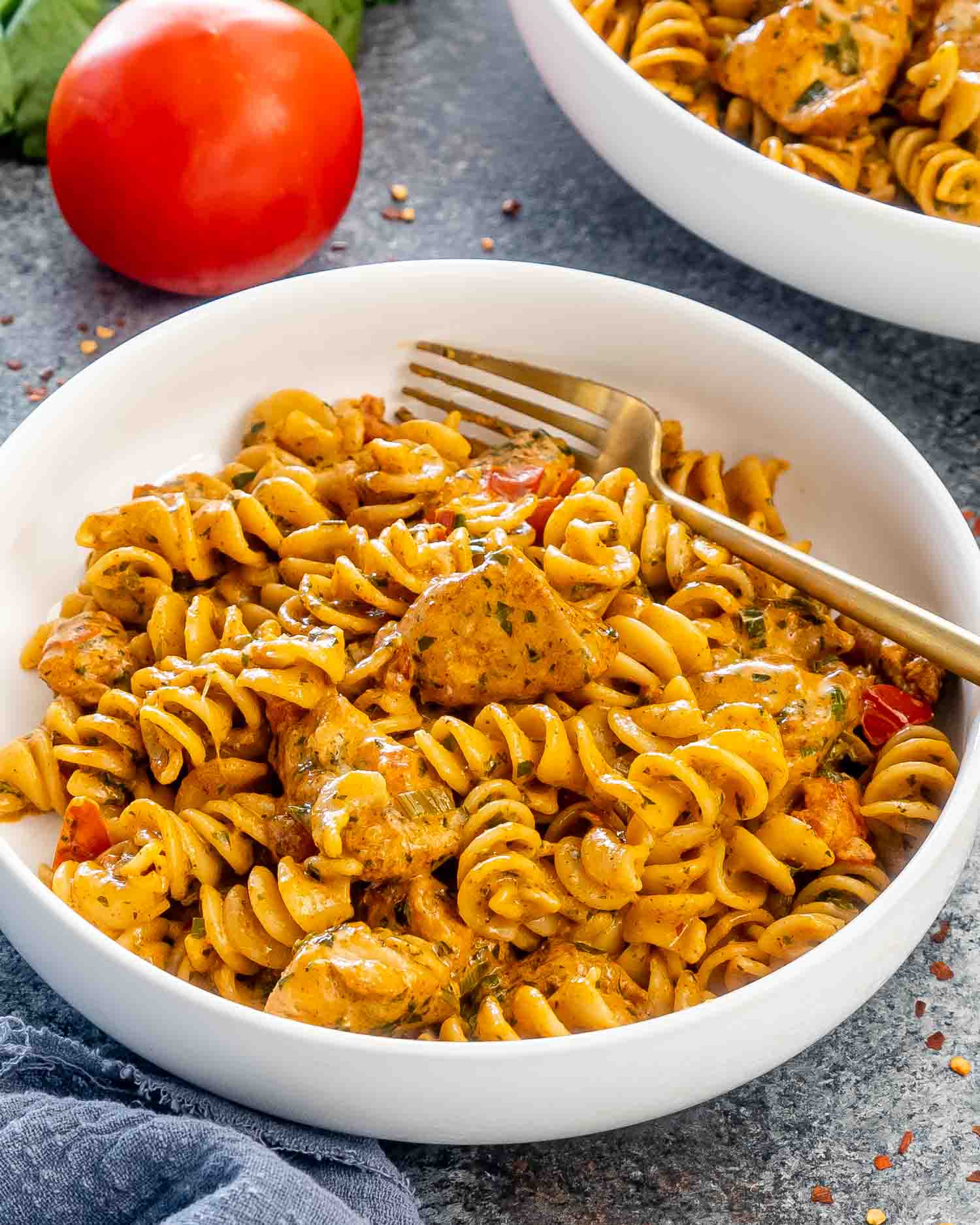 creamy tomato chicken pasta in a white bowl with a fork in it.