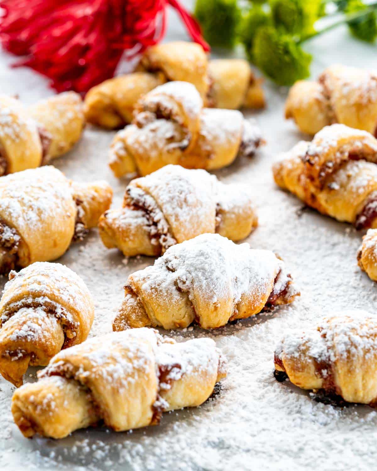 rugelach cookies with powdered sugar on a piece of parchment paper.