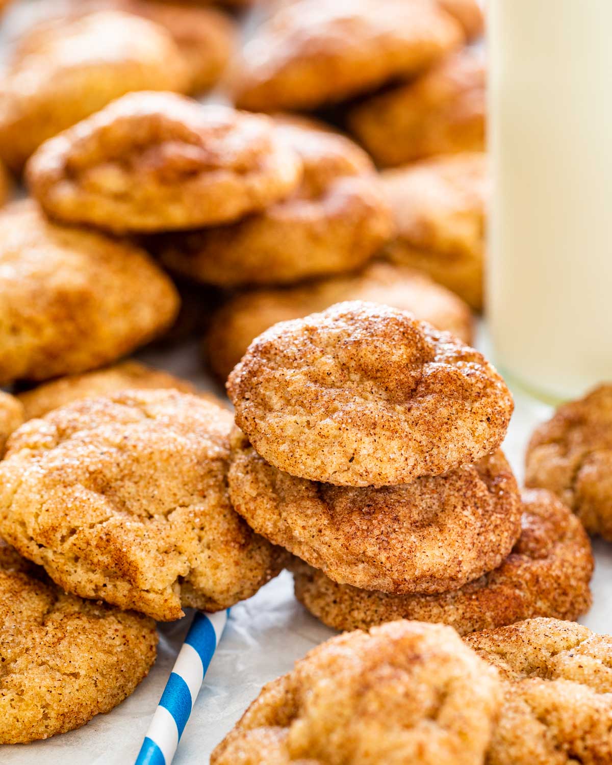 a bunch of snickerdoodle cookies stacked on top next to a bottle of milk.