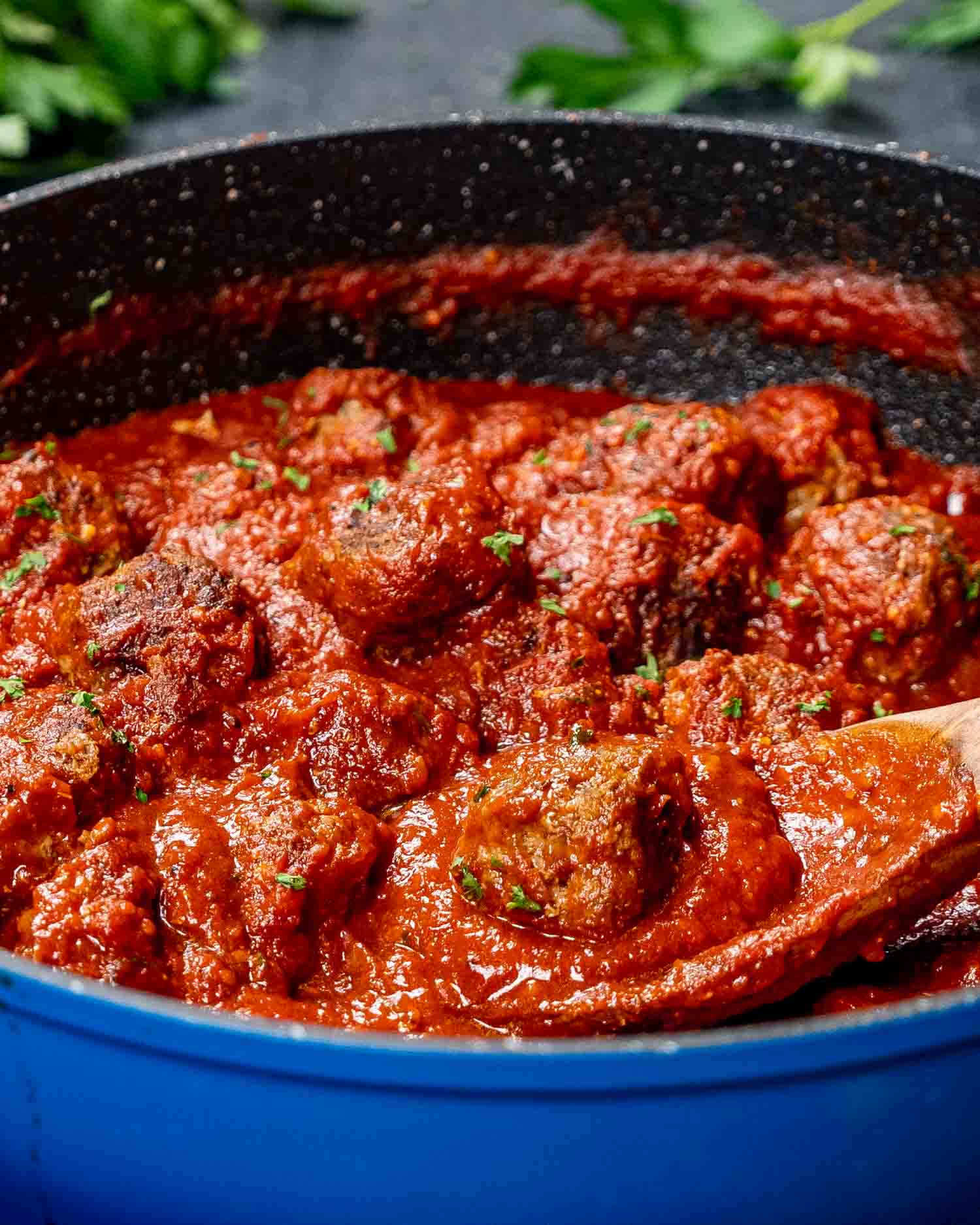 a skillet with freshly made meatballs with sauce.