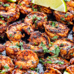 blackened shrimp with lime wedges in a black skillet.